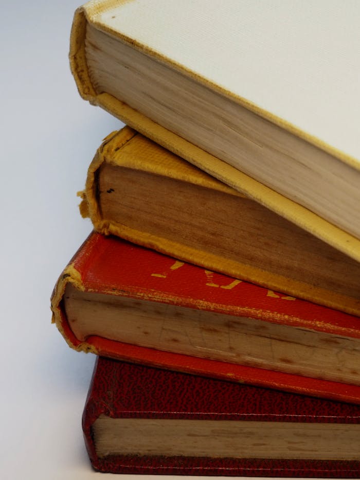 A stack of vintage hardcover books showcasing worn and aged spines.